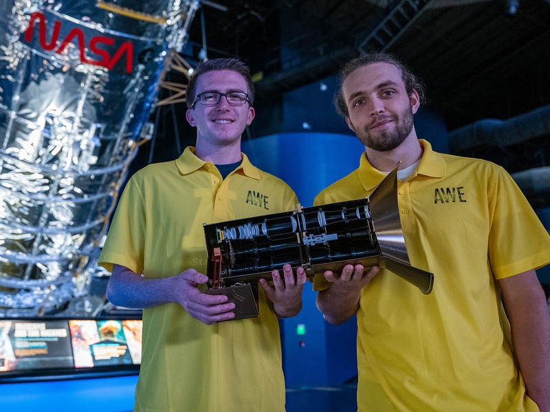 Two students hold an instrument that will be used in space.